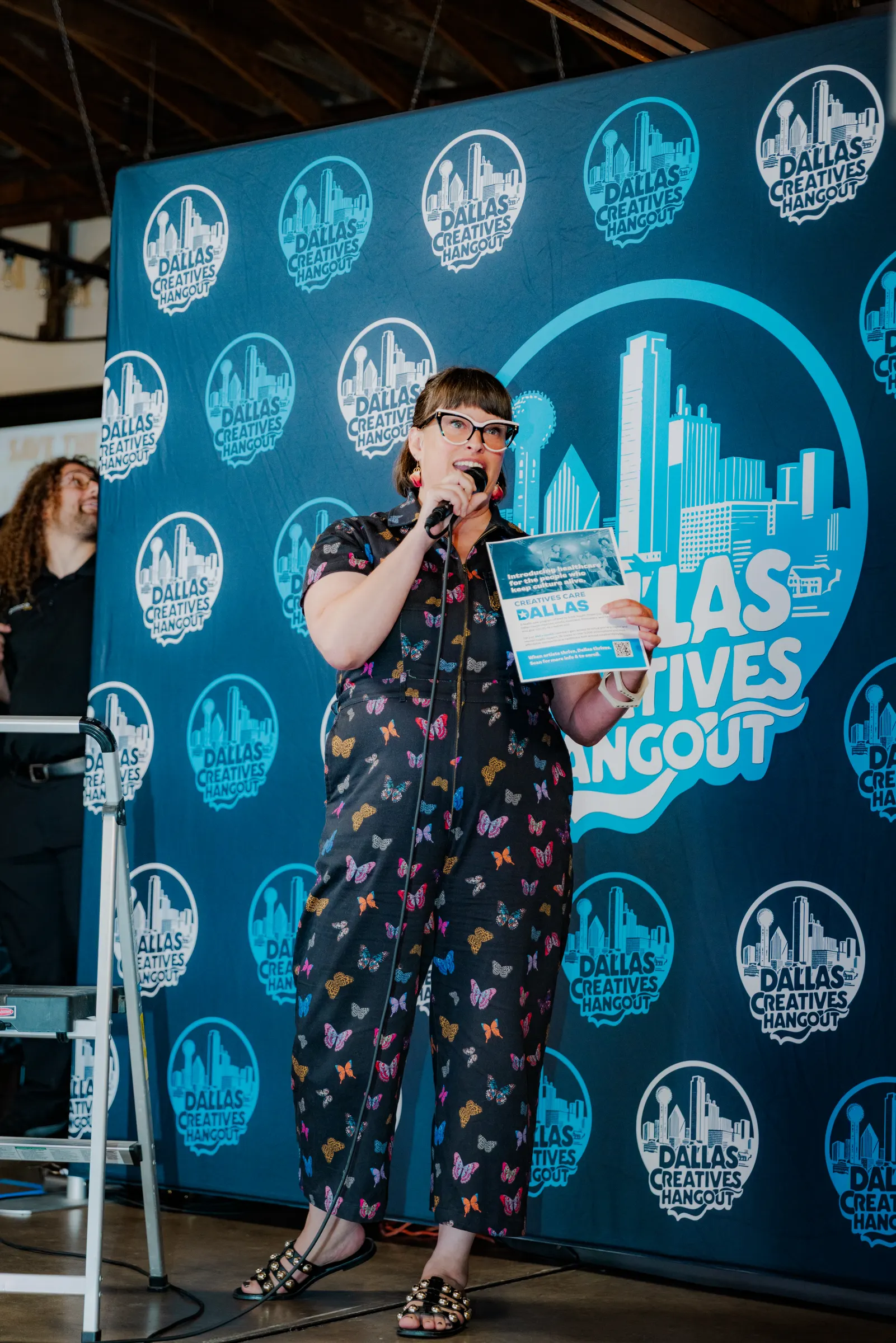A speaker on the mic in front of the Hangout backdrop